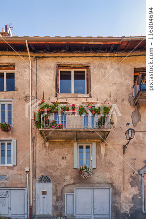 Architectural of brown facade building with windows and balcony has a flower box blooming 116804694