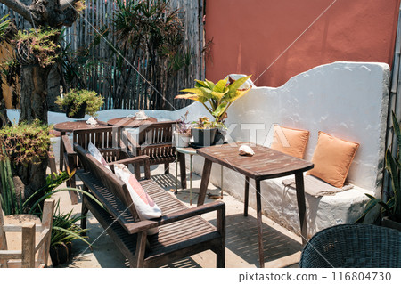 Patio with wooden table, chair and bench with plant decoration on the outside Patio with wooden table, chair and bench with plant decoration on the outside 116804730
