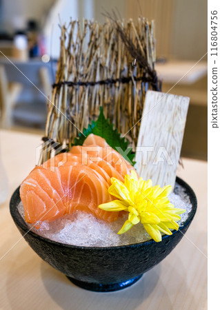 Ceramic bowl of sliced salmon sushi with yellow flower on crushed ice Ceramic bowl of sliced salmon sushi with yellow flower on crushed ice 116804756