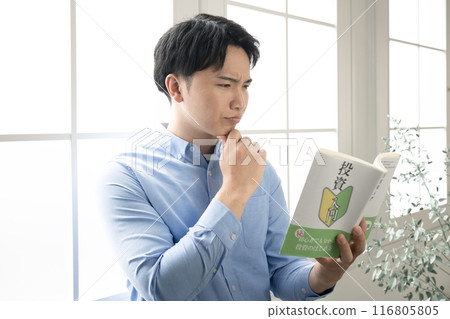 A man reading an investment book by the window A man reading an investment book by the window 116805805