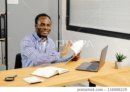 Man sitting at desk holding paper Man sitting at desk holding paper 116806229