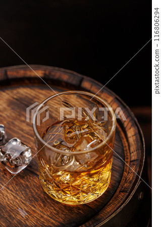 Whiskey glass with ice on a rustic barrel, a classic sip 116806294