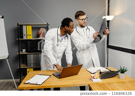 Two men in white lab coats analyzing xray Two men in white lab coats analyzing xray 116806326