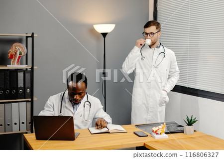 Doctor discussing diagnosis with young colleague in office Doctor discussing diagnosis with young colleague in office 116806327