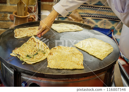 Hand of woman, process of preparing gozleme, authentic food. Concept of national food Hand of woman, process of preparing gozleme, authentic food. Concept of national food 116807346