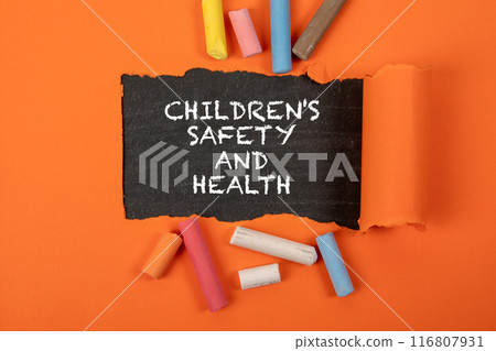 CHILDREN'S SAFETY AND HEALTH. Text under torn orange paper on a blackboard CHILDREN'S SAFETY AND HEALTH. Text under torn orange paper on a blackboard 116807931