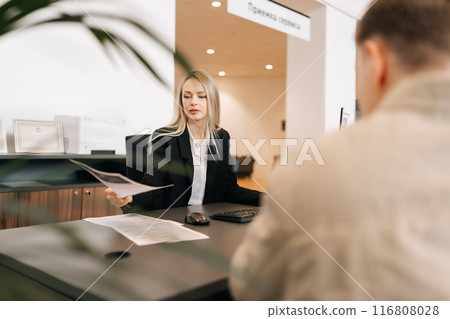 Serious female financial advisor, attorney lawyer or bank manager consulting unrecognizable male client investor receiving document at business meeting, reviewing legal paper file, planning taxes. Serious female financial advisor, attorney lawyer or bank manager consulting unrecognizable male client investor receiving document at business meeting, reviewing legal paper file, planning taxes. 116808028