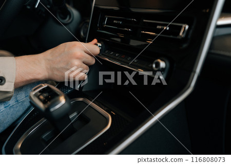 Closeup hands of driver male adjusting temperature in car by rotate. Close-up of man hand hold button of temperature. Close up of human hand rotating car temperature control. 116808073