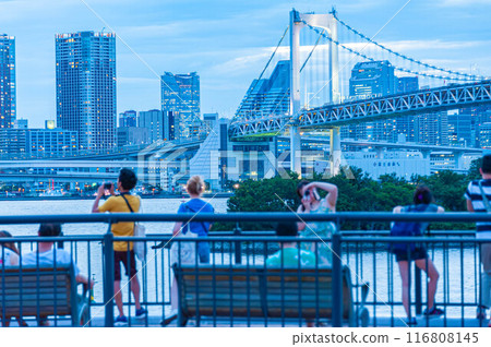 Tourists looking out over the Rainbow Bridge and the buildings of central Tokyo from the observation deck Tourists looking out over the Rainbow Bridge and the buildings of central Tokyo from the observation deck 116808145