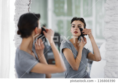 Facial skin care. A woman is doing a face massage using gouache stones. Facial skin care. A woman is doing a face massage using gouache stones. 116808390
