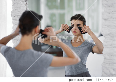 Facial skin care. A woman is doing a face massage using gouache stones. Facial skin care. A woman is doing a face massage using gouache stones. 116808392