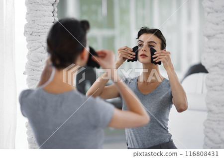 Facial skin care. A woman is doing a face massage using gouache stones. 116808431