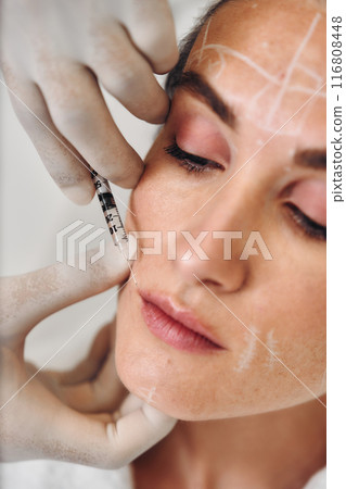A woman gets injections in the face. 116808448