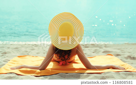 Summer vacation, beautiful happy relaxing young woman with tourist hat lying on the beach at sea 116808581