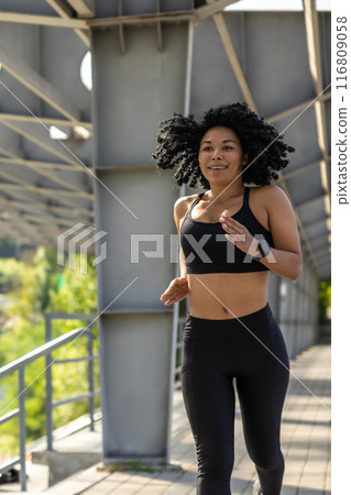 Brunette woman in black top running and looking concentrated 116809058