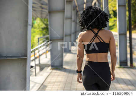 Woman in black sportswear on the bridge with her ack to the camera Woman in black sportswear on the bridge with her ack to the camera 116809064