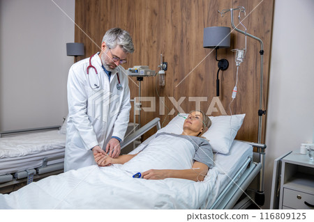 Doctor having an examination of a patient in an intensive therapy unit Doctor having an examination of a patient in an intensive therapy unit 116809125