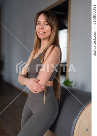 Pilates fitness trainer in pilates studio. Young sporty attractive woman wearing sportswear in yoga studio. Fit, healthy and strong authentical body. Fitness concept 116809351
