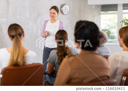 Female teacher giving lecture to group of students in classroom 116810411