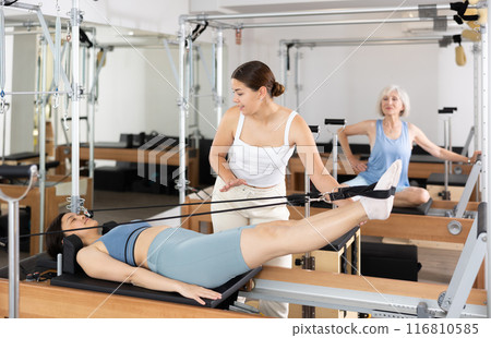 Female pilates trainer helping pilates woman during training 116810585
