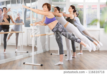 Middle aged woman learning arabesque in ballet class for beginners 116810718