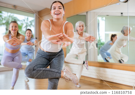 Ordinary active females exercising dance moves in modern dance studio 116810758