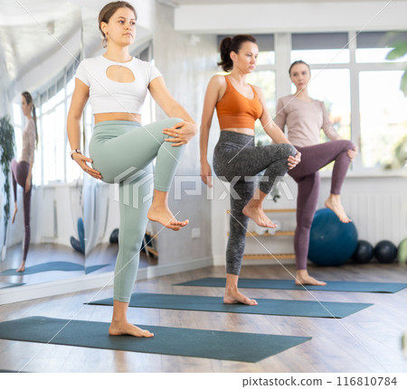Girl teacher lead yoga lesson for girls and doing Utchicha Hasta padangusthasana. 116810784