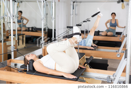 Concentrated young girl practicing exercises on Pilates reformer Concentrated young girl practicing exercises on Pilates reformer 116810866