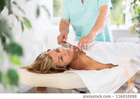 Male therapist covers woman client with white terry sheet after relaxing massage procedure Male therapist covers woman client with white terry sheet after relaxing massage procedure 116810898