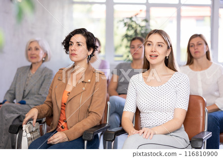 Positive female students listening to lecture in lecture hall 116810900