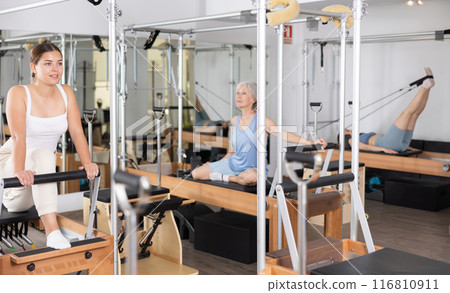Concentrated young girl practicing exercises on Pilates reformer 116810911