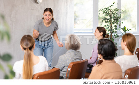 Positive young girl giving lecture to group of women Positive young girl giving lecture to group of women 116810961