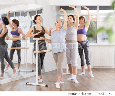 Adult woman teacher correcting beginning dancers Adult woman teacher correcting beginning dancers 116810969