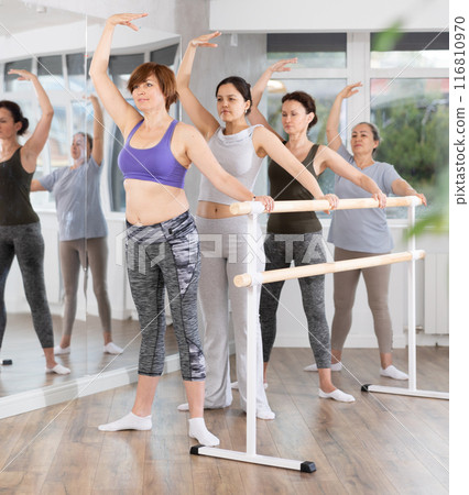Mature woman practicing second position in amateur group ballet class Mature woman practicing second position in amateur group ballet class 116810970