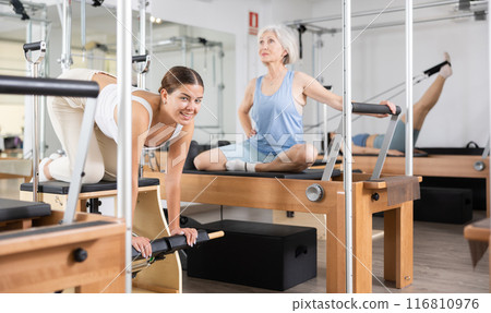 Young woman doing pilates exercises with reformer bed Young woman doing pilates exercises with reformer bed 116810976