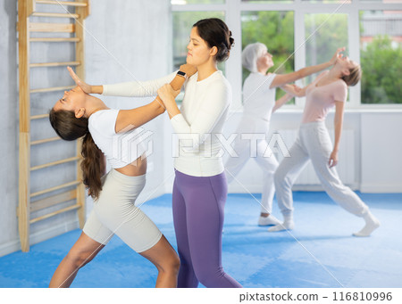 Woman and girl in gym perform basic elements of krav maga self-defense system. 116810996
