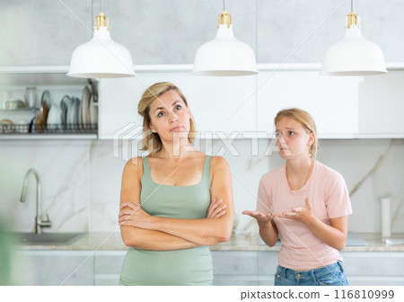Agitated daughter imploringly asks angry mother for forgiveness. 116810999