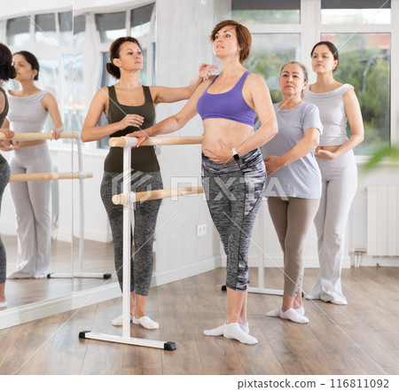 Adult woman teacher correcting beginning dancers 116811092