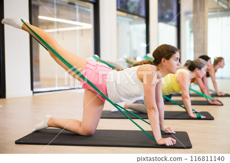 Beautiful female doing pilates exercise with expander tape Beautiful female doing pilates exercise with expander tape 116811140