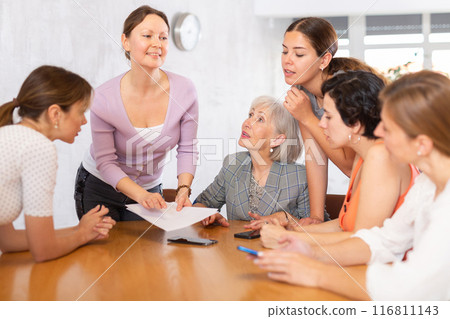 Smiling woman conducting informal work meeting with female colleagues Smiling woman conducting informal work meeting with female colleagues 116811143