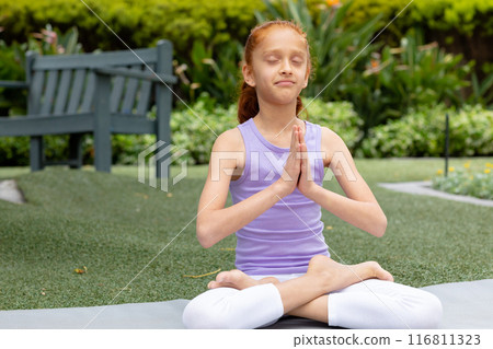 Biracial girl meditates cross-legged in garden, space for text Biracial girl meditates cross-legged in garden, space for text 116811323