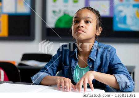 Blind biracial schoolgirl sitting at desk in class reading braille, with copy space Blind biracial schoolgirl sitting at desk in class reading braille, with copy space 116811381