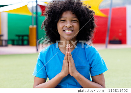 Portrait of smiling biracial schoolgirl practicing yoga meditation in schoolyard, with copy space Portrait of smiling biracial schoolgirl practicing yoga meditation in schoolyard, with copy space 116811402