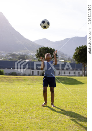 Happy african american schoolboy playing football on field at school Happy african american schoolboy playing football on field at school 116811502
