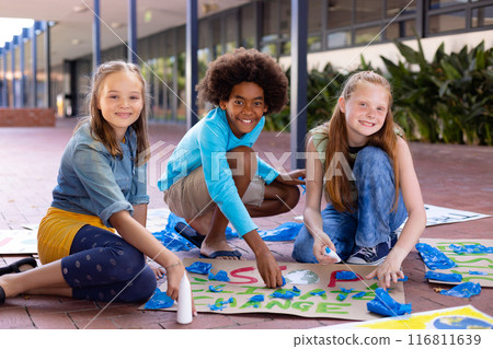 Portrait of happy diverse schoolchildren making ecology posters during outdoor school art class 116811639
