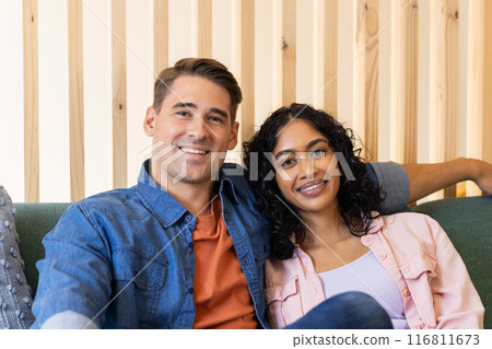 Smiling young couple sitting on couch, enjoying time together indoors 116811673