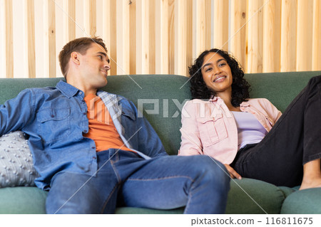 Relaxing on couch, young couple smiling and enjoying time together indoors 116811675