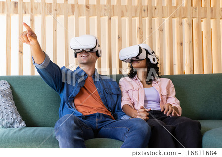 Using VR headsets, young couple experiencing virtual reality on couch 116811684