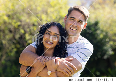 Embracing and smiling, young couple outdoors in park setting Embracing and smiling, young couple outdoors in park setting 116811721