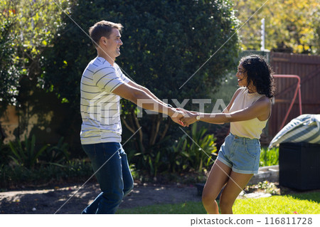Young couple dancing and holding hands outdoors, enjoying sunny day together Young couple dancing and holding hands outdoors, enjoying sunny day together 116811728